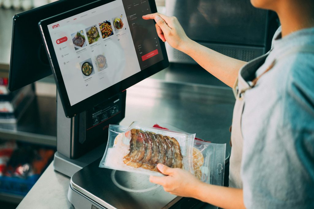 Person using digital POS system in a restaurant for cashless food payment.